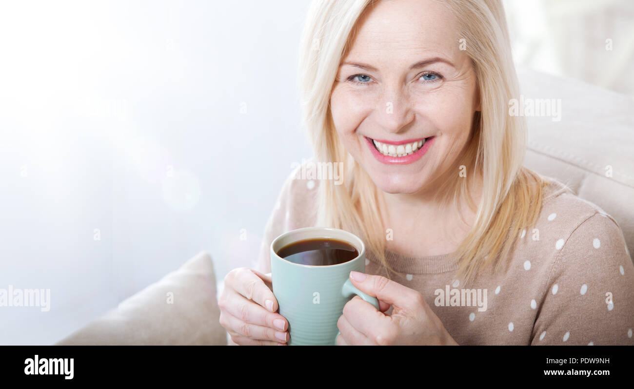 Portrait of happy middle aged woman with mug in hands Stock Photo