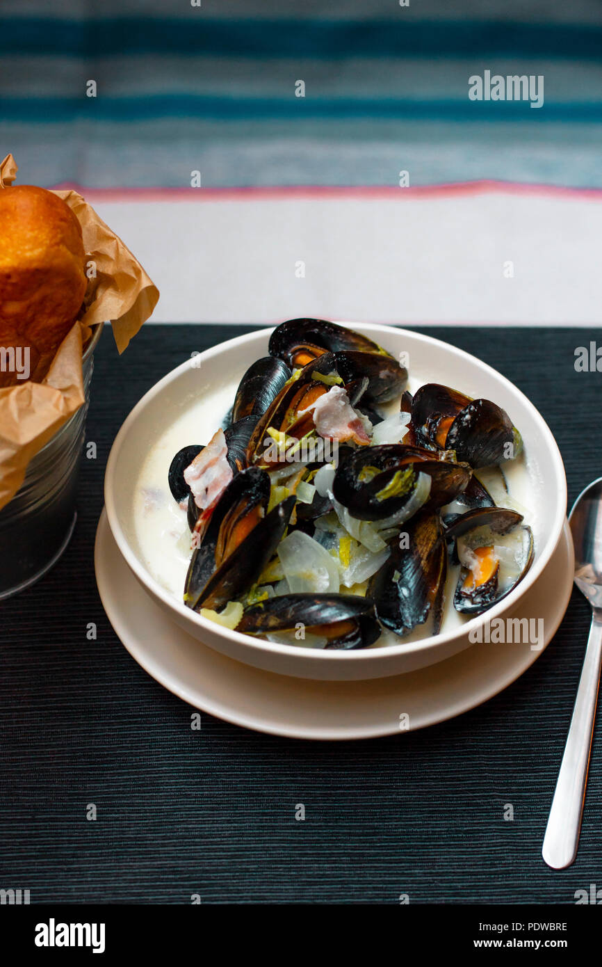 Mussels with onions and bacon in cream sauce in deep plate Stock Photo