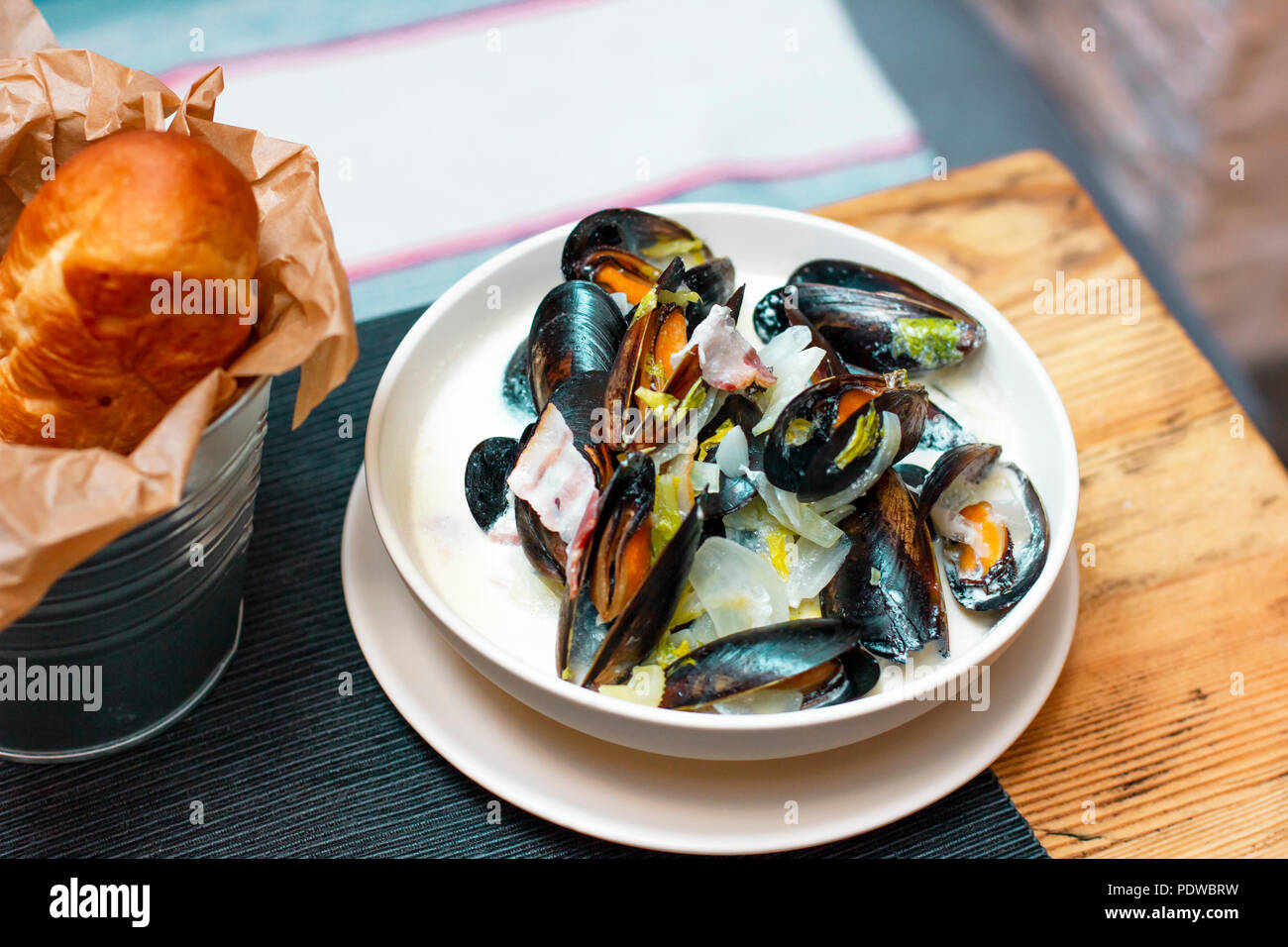 Mussels with onions and bacon in cream sauce in deep plate with bread