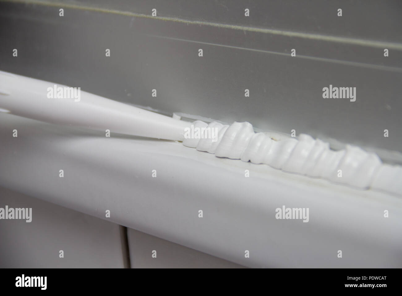 Close up Plumber applying silicone sealant to the countertop and