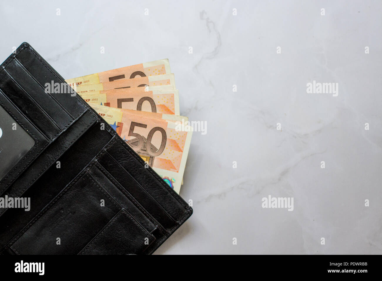 banknotes 50 euros in a man's leather purse on the marble background. Top view Men's wallet with cash euro. Stock Photo