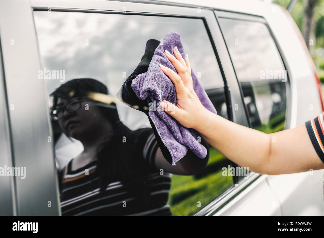 Closeup picture, image young woman, driver, dry wiping her car with microfiber cloth after