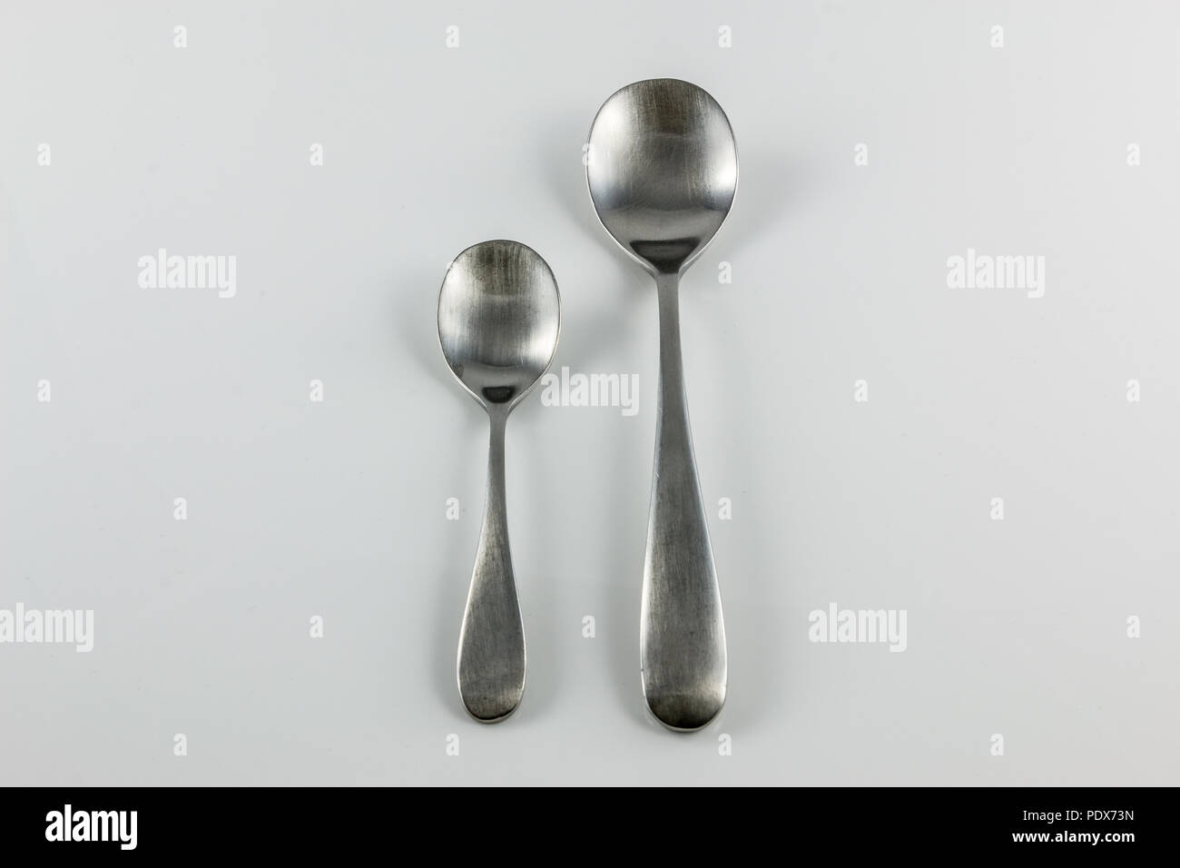 Steel cutlery with table spoon and little spoon Stock Photo