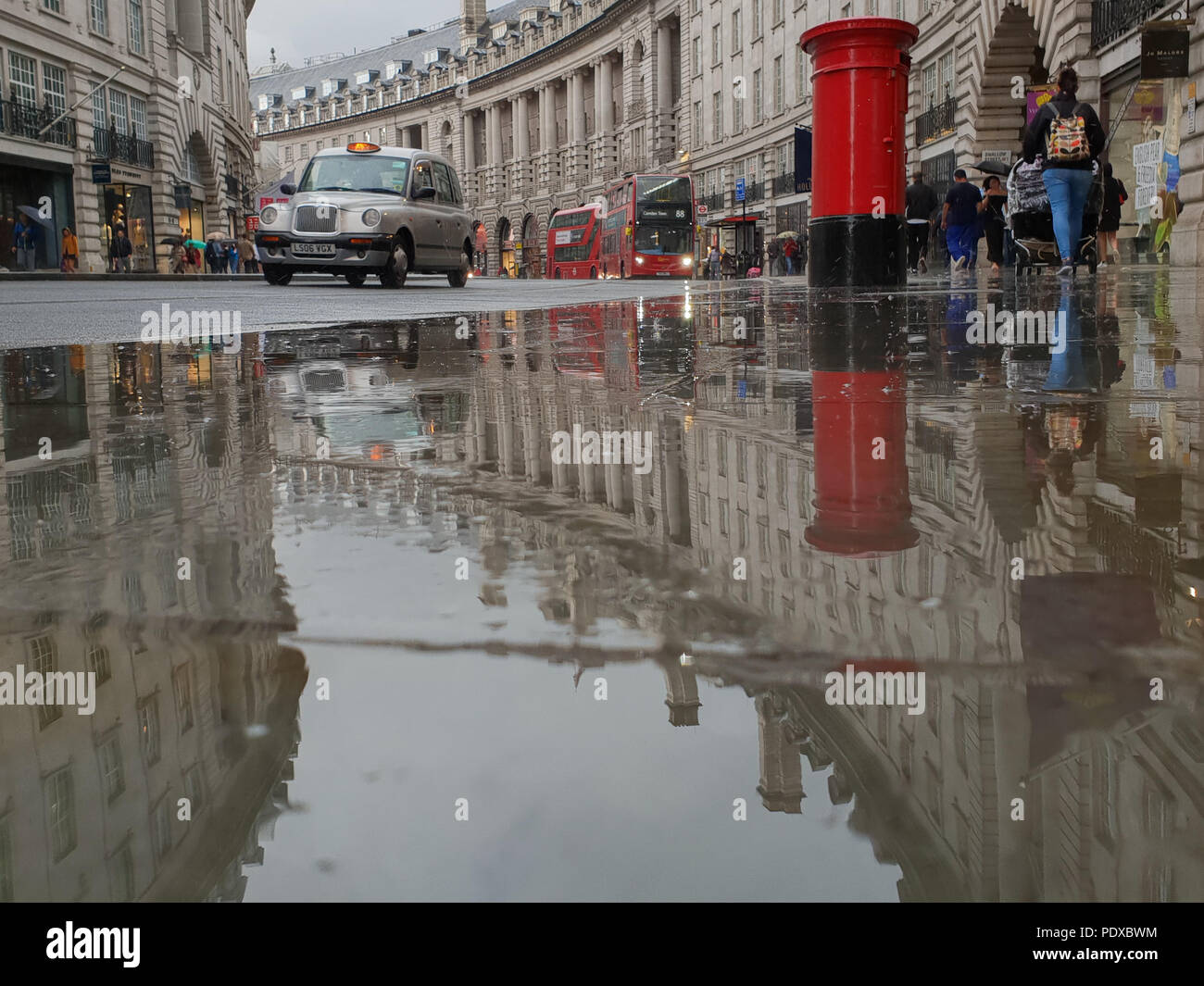 Regents Street. London. UK 10 Aug 2018 - A reflection of London black taxi and a postbox in a large puddle of rain water in Regent Street after a heavy rainfalls in central London. Credit Roamwithrakhee /Alamy Live News Stock Photo