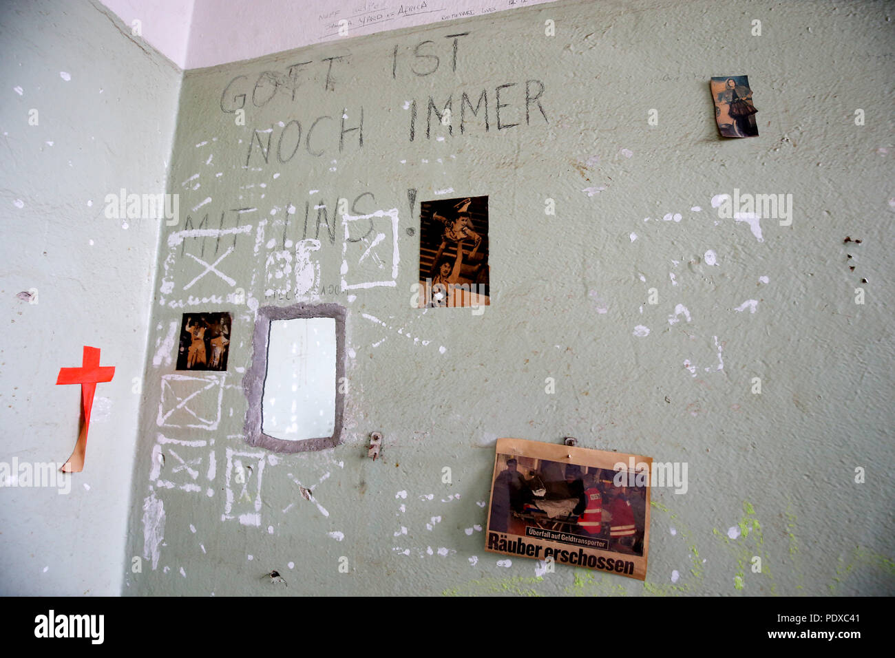 Berlin, Germany. 10th Aug, 2018. The inscription 'God is still with us' and newspaper clippings are attached to a cell wall in a former GDR police prison on Keibelstrasse in the 'Mitte' district. The Education Administration of the Senate organized a tour for journalists through the former GDR police prison. An educational centre for students is to be built on the floors with the cell sections.s. Credit: Wolfgang Kumm/dpa/Alamy Live News Stock Photo
