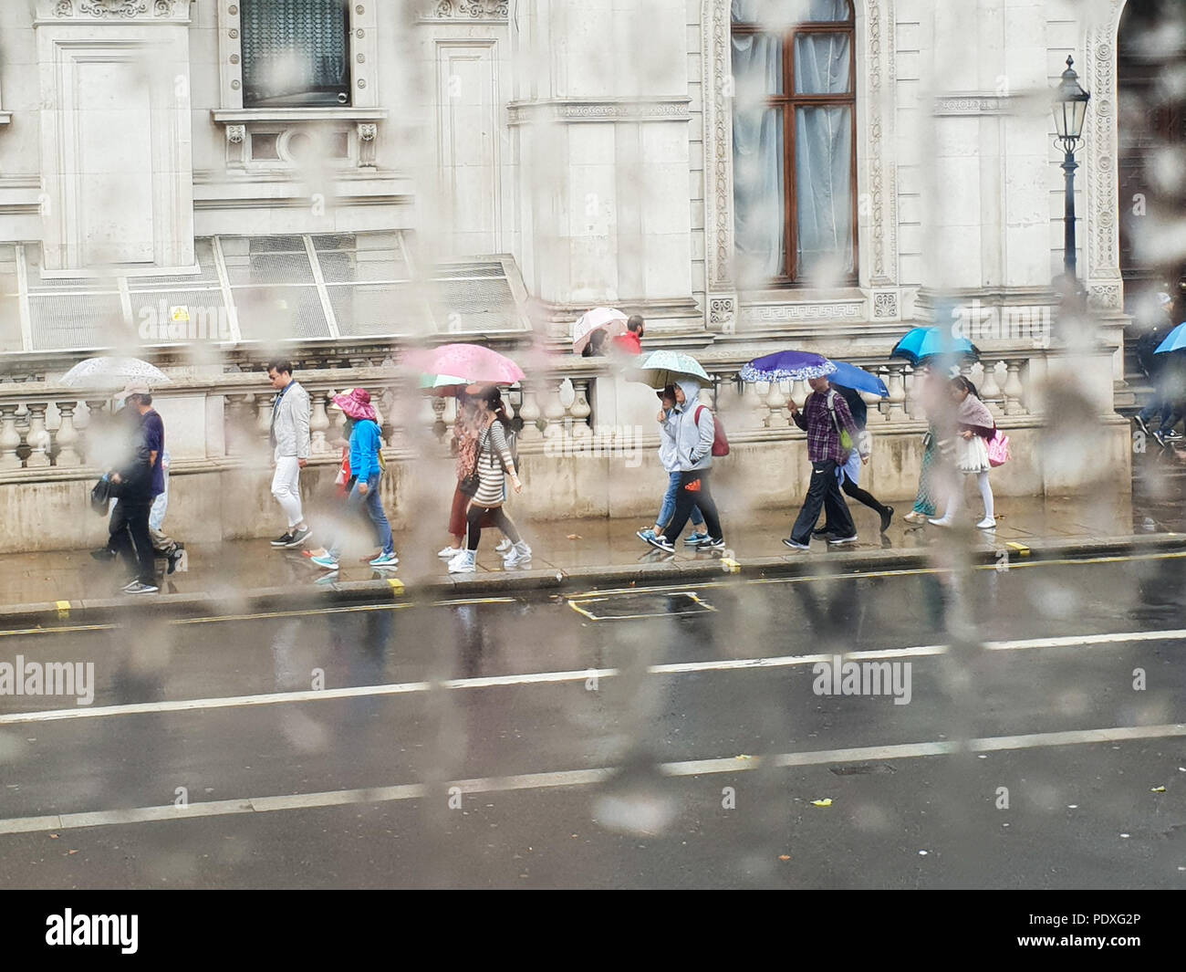 Westminster. London. UK 10 Aug 2018 - View of tourists with umbrellas on Whitehall through a double decker bus window covered with raindrops.  Credit Roamwithrakhee /17�Թ����� Live News Stock Photo