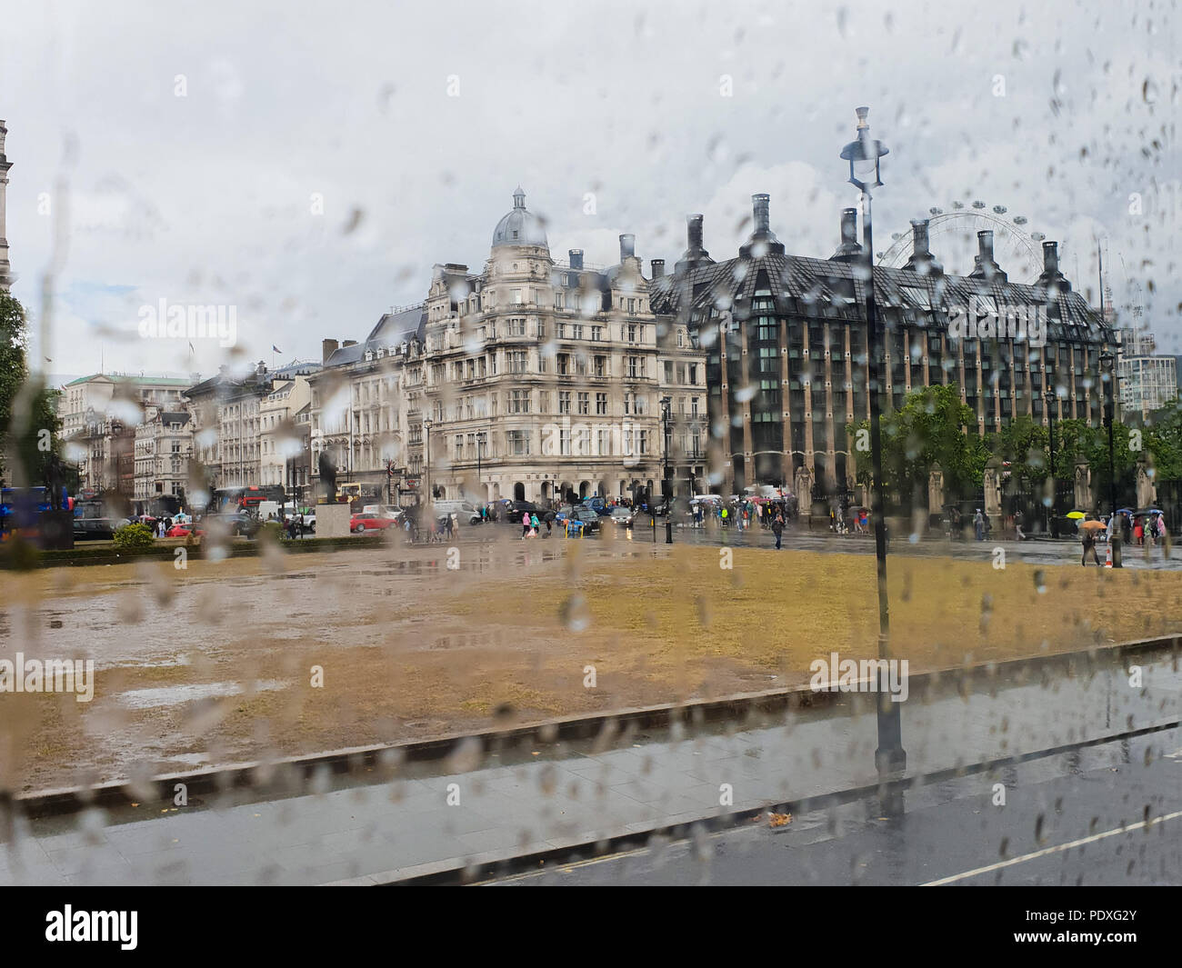 Westminster. London. UK 10 Aug 2018 - View of Portcullis House and London Eye through a double decker bus window covered with raindrops.  Credit Roamwithrakhee /17�Թ����� Live News Stock Photo