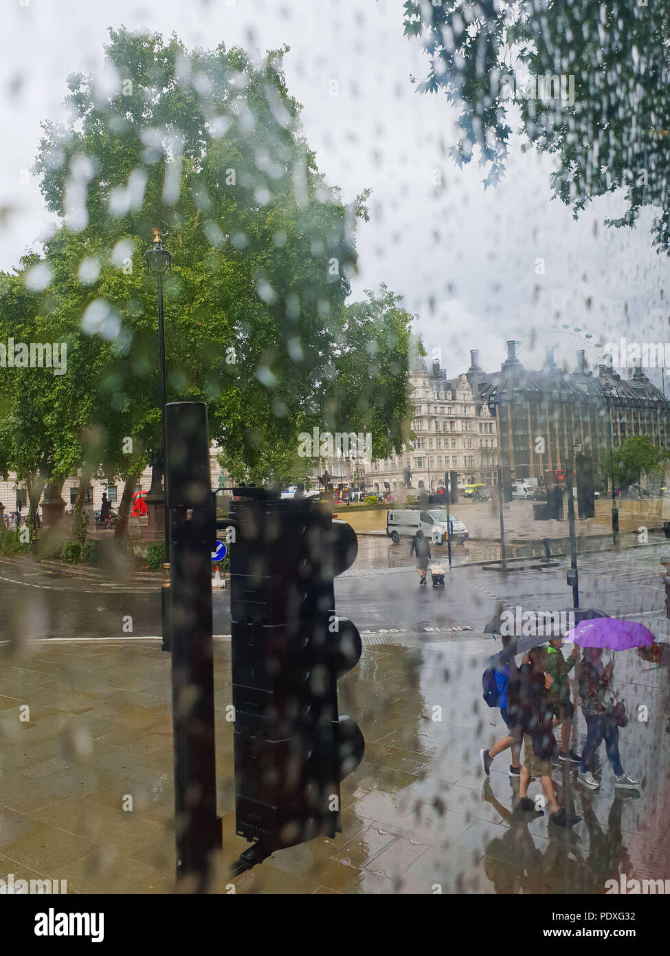 Westminster. London. UK 10 Aug 2018 - View of Portcullis House and London Eye through a double decker bus window covered with raindrops.  Credit Roamwithrakhee /17�Թ����� Live News Stock Photo