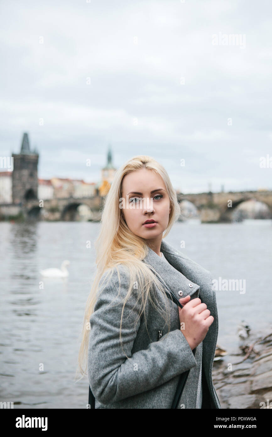 Fashionable Blonde With Long Hair In A Coat Near Charles Bridge In