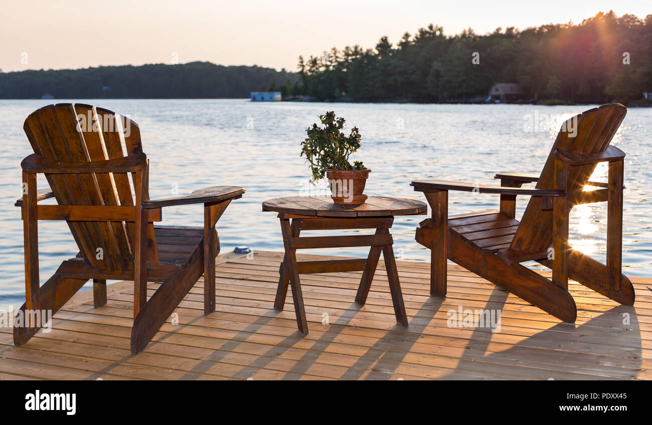 Chairs on a deck overlooking a lake at sunset Stock Photo Alamy