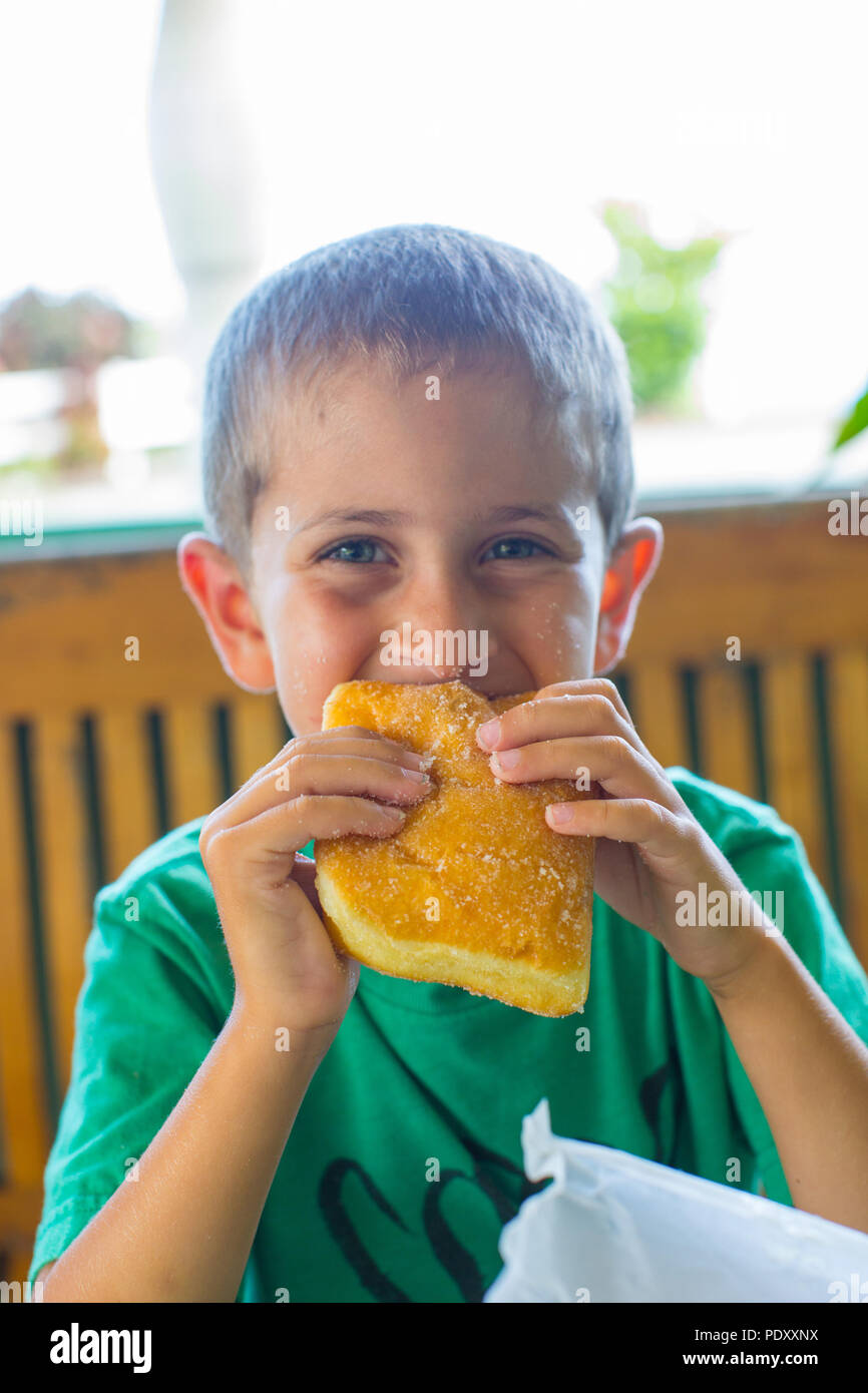 Young Boy Eating Malasada, Hawaii, USA Stock Photo