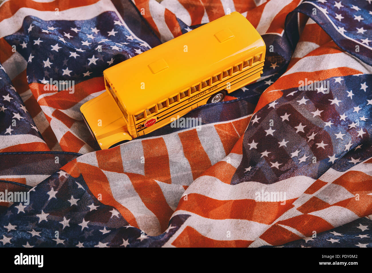Yellow school bus children educational transport with signs in Close up of school bus in American flag waving in the wind. Stock Photo