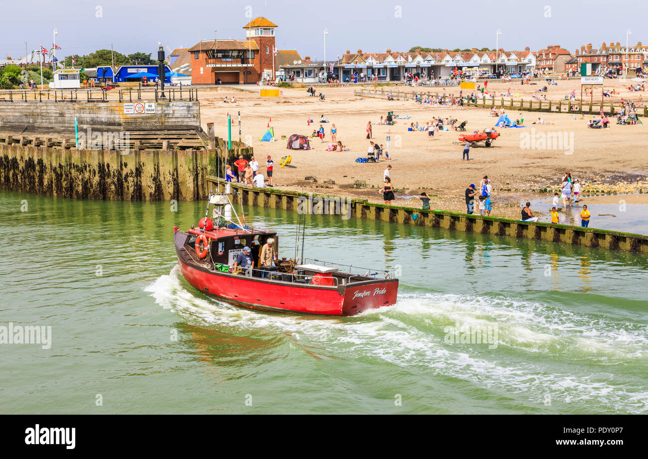 Small red fishing boat entering the River Arun by West Beach, Littlehampton, a small holiday resort on the south coast in West Sussex, UK in summer Stock Photo