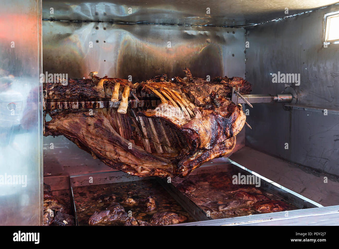 Roasted ox on a skewer, portions cut off in holding pans, Bavaria, Germany Stock Photo