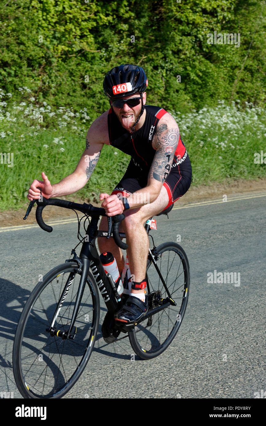 Male athlete competing in the Cotswold Triathlon just completing the bike stage Stock Photo