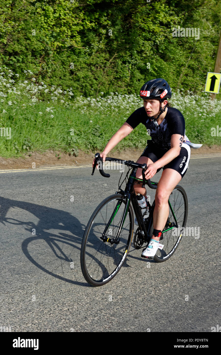 Female athlete competing in the Cotswold Triathlon just completing the bike stage Stock Photo