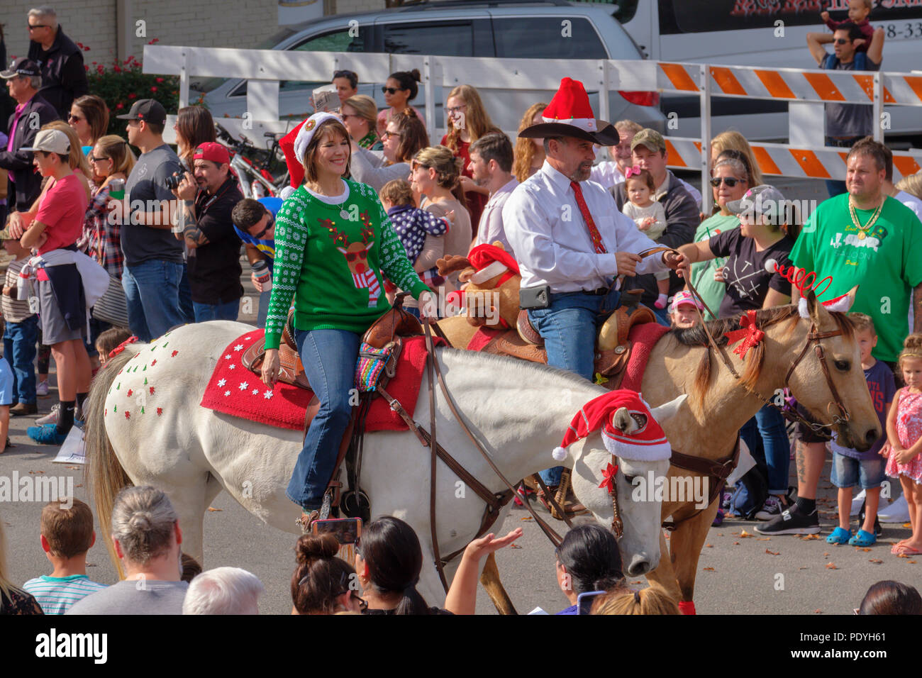 Two horse back riders with Christmas hats in Georgetown, Texas annual Christmas parade with crowds looking on. Stock Photo