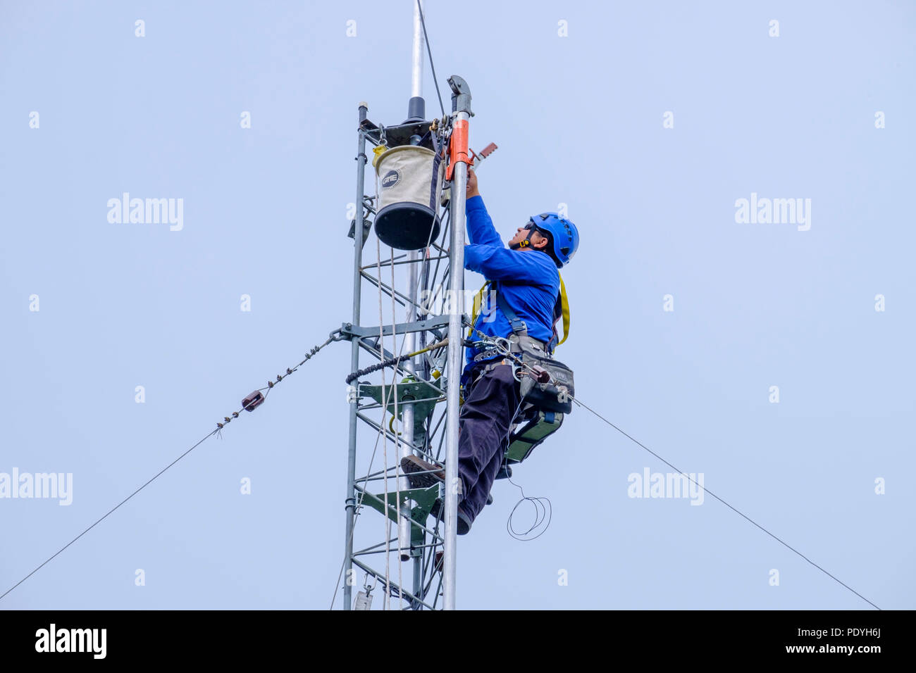 Telecom tower climber working at top of radio tower. Stock Photo