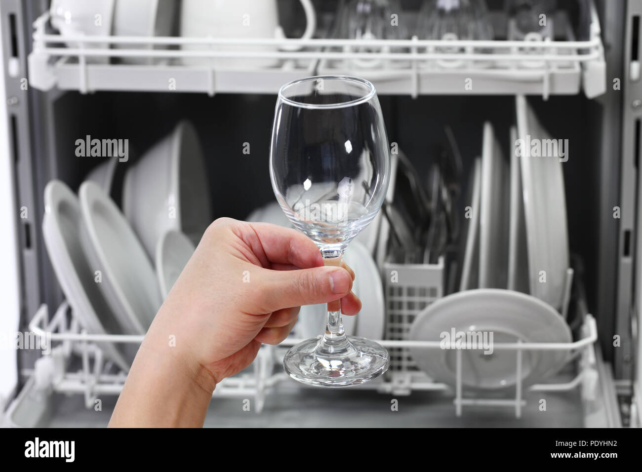 dishwasher, open and loaded with dishes, man hand taking out clean wine