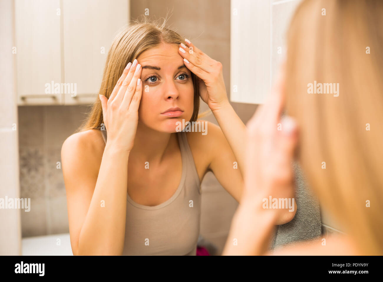 Worried woman is looking her first wrinkles in the bathroom Stock Photo