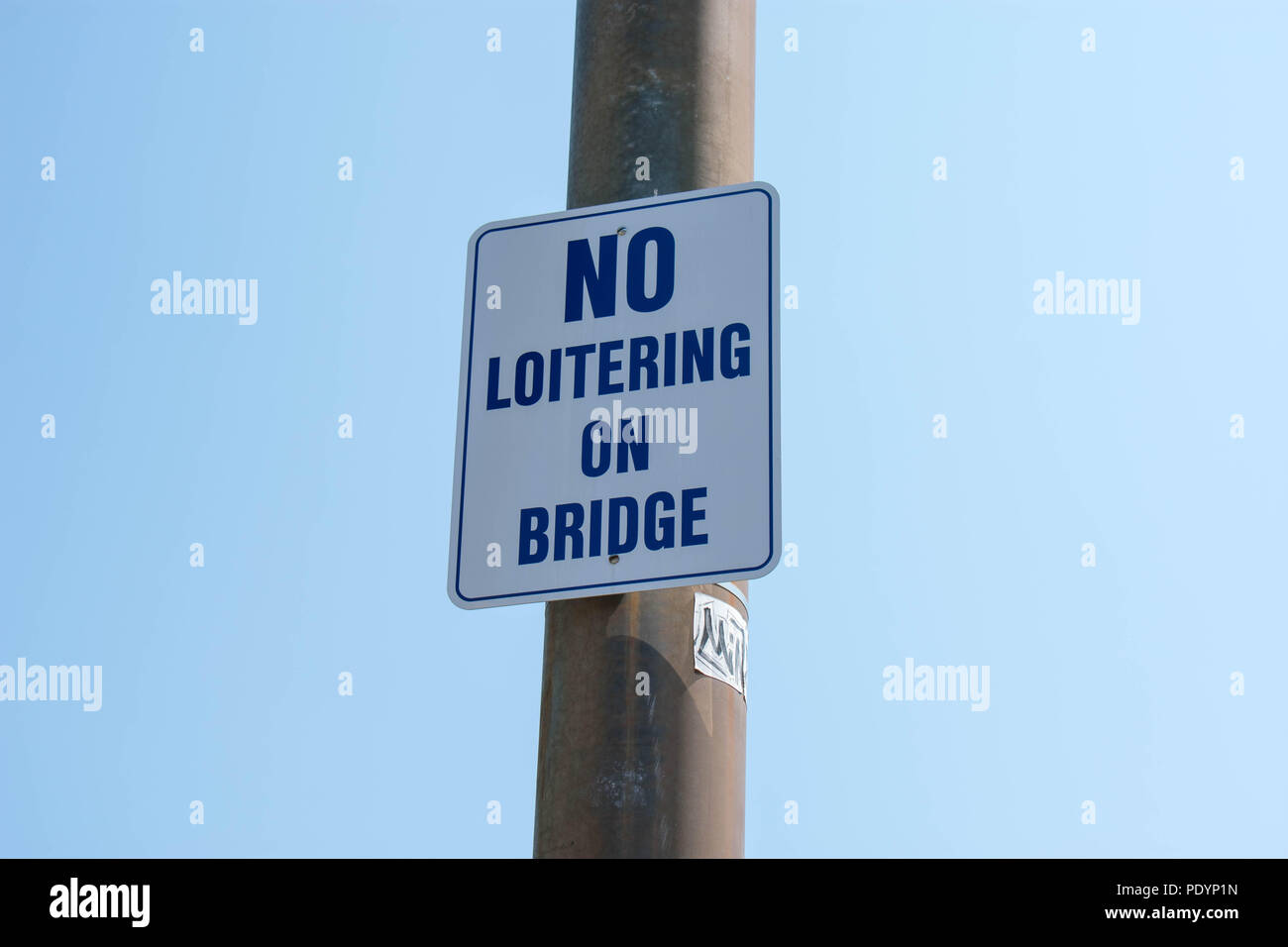 No loiterig on bridge sign with a plain light blue backround. Stock Photo