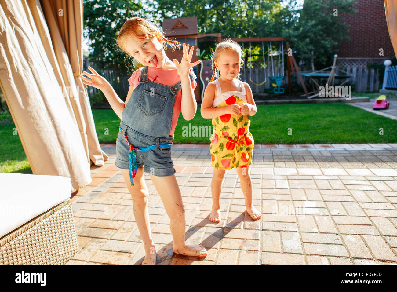Portrait of  two little girls  sisters having fun on home backyard. Friends girls making silly faces. Lifestyle family moment of siblings playing toge Stock Photo