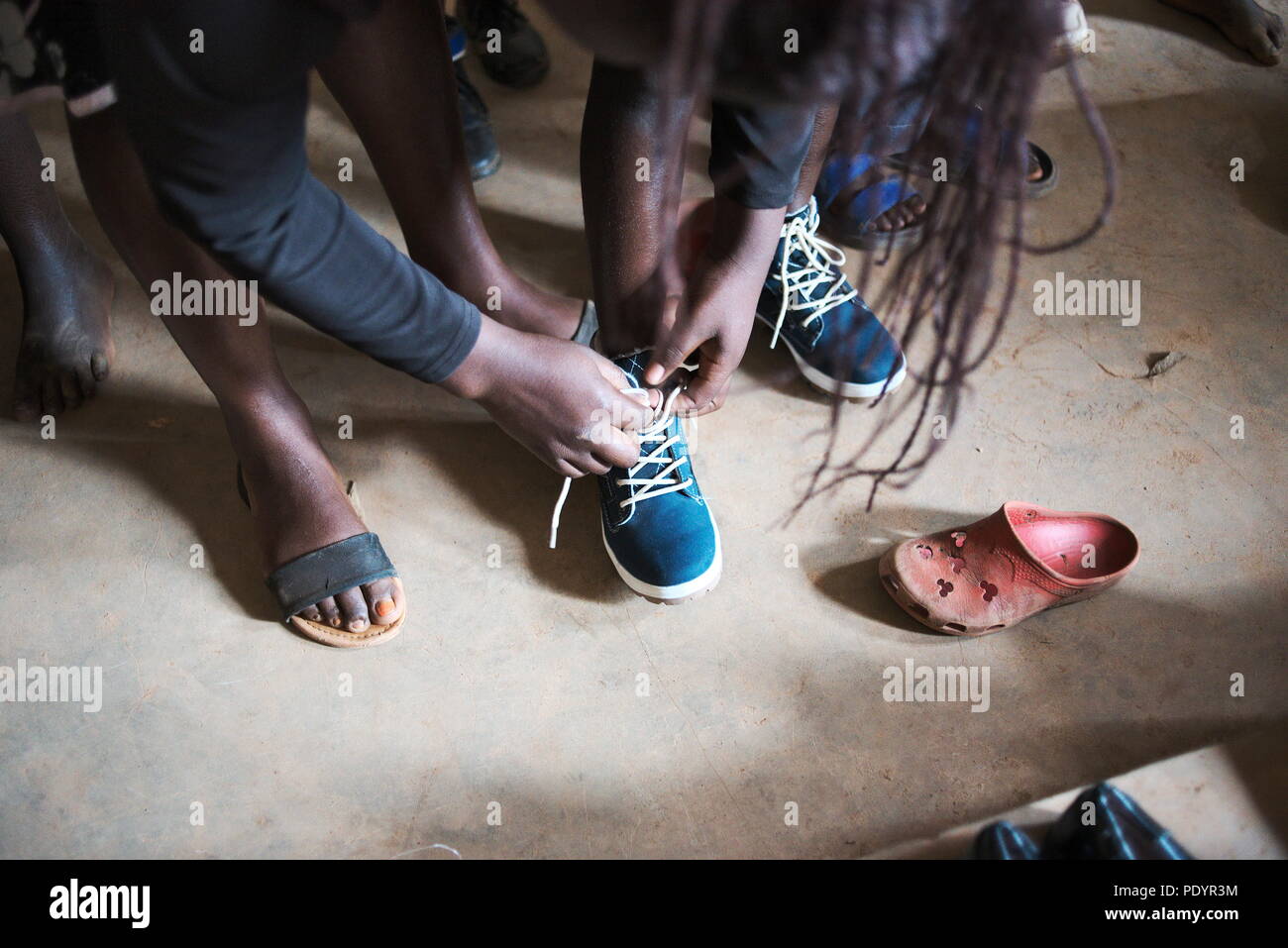 Young Ugandan/African schoolchildren try on used shoes given to the school as a gift from the UK Stock Photo