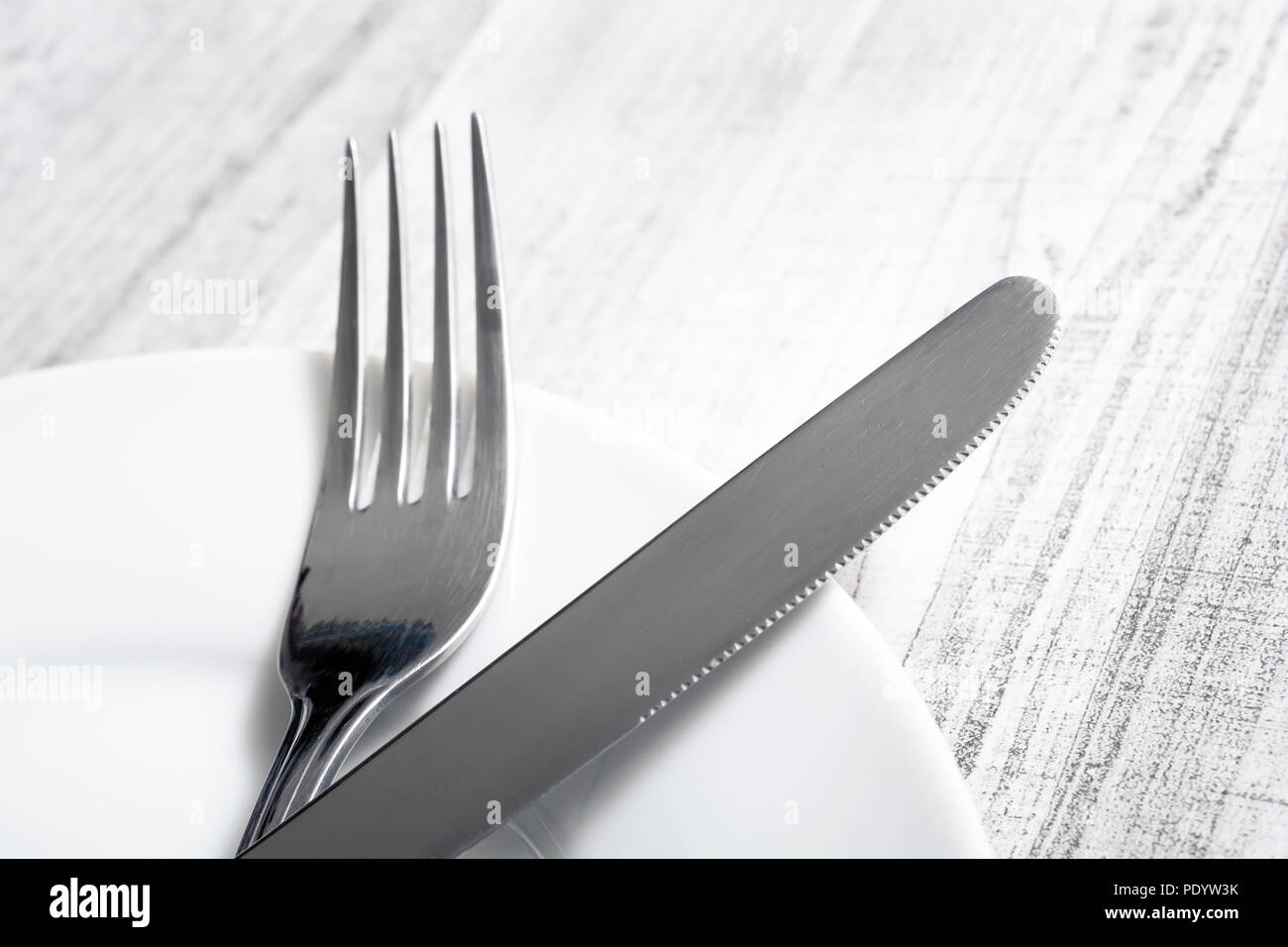 Set Of Crossed Stainless Steel Fork And Knife Lying On A Dinner Plate