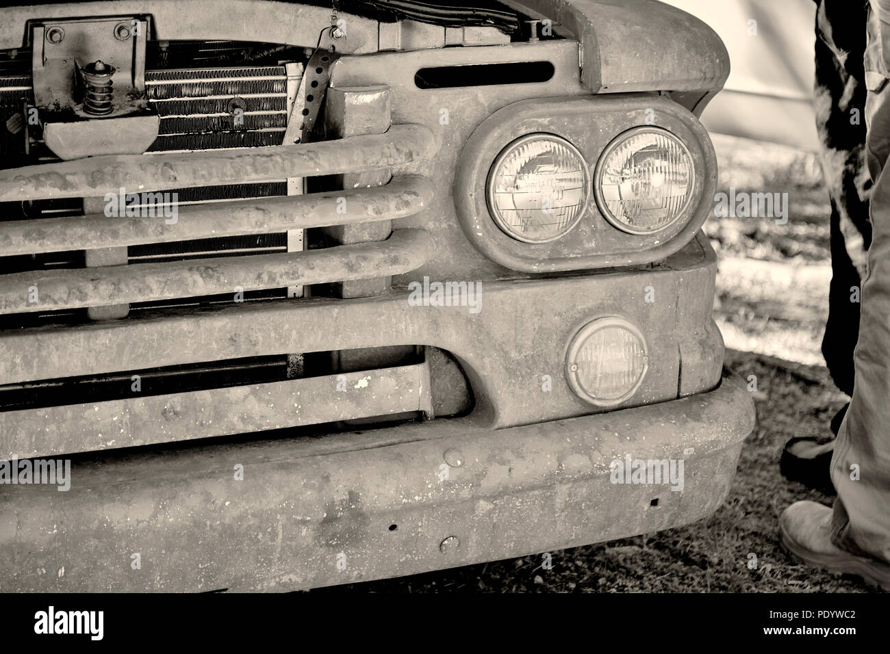 Front grill and headlight of an antique rusty old pick up truck in black and white with shallow depth of field Stock Photo