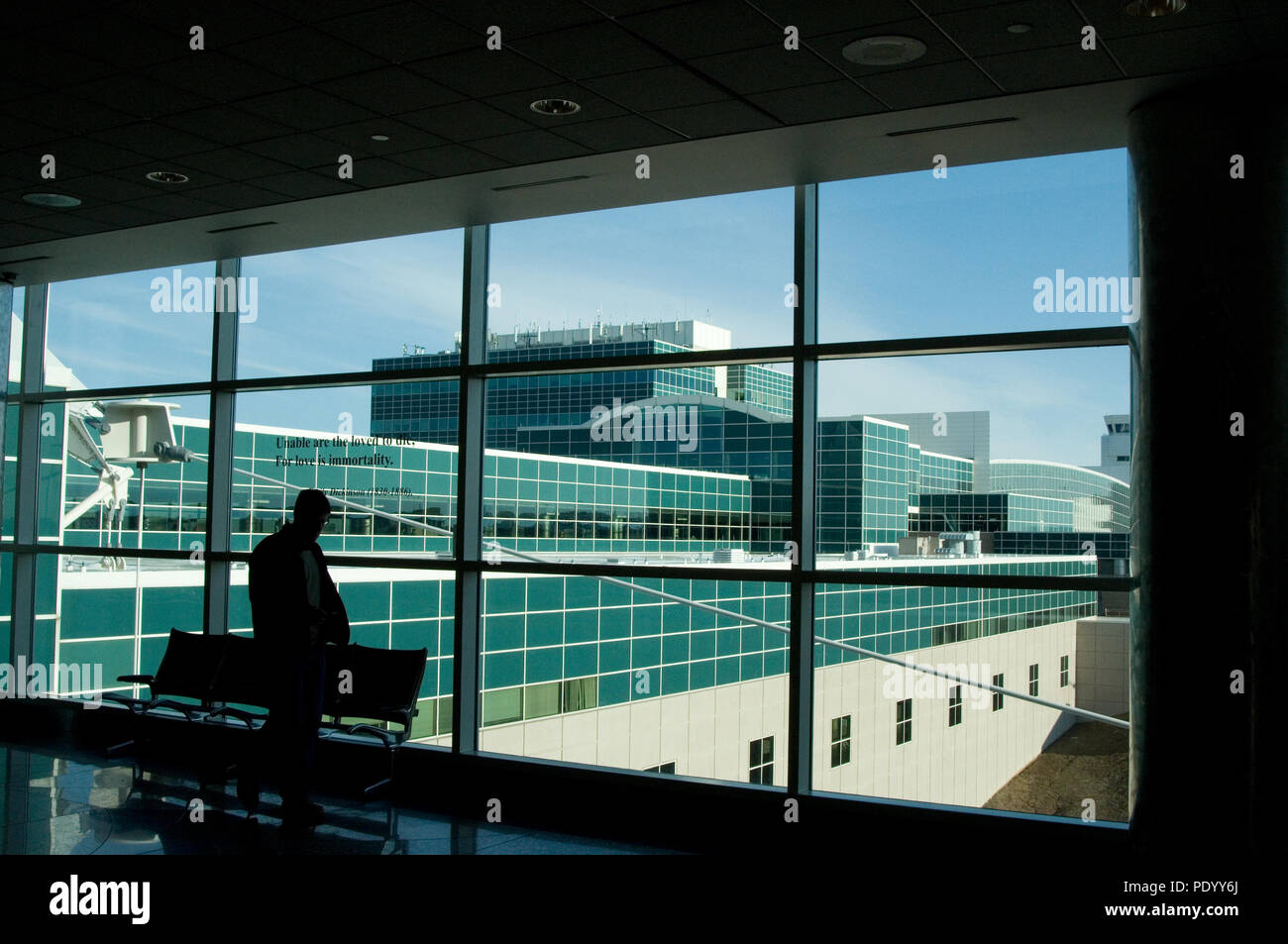 Silhouette of a man looking out the airport concourse window. Stock Photo