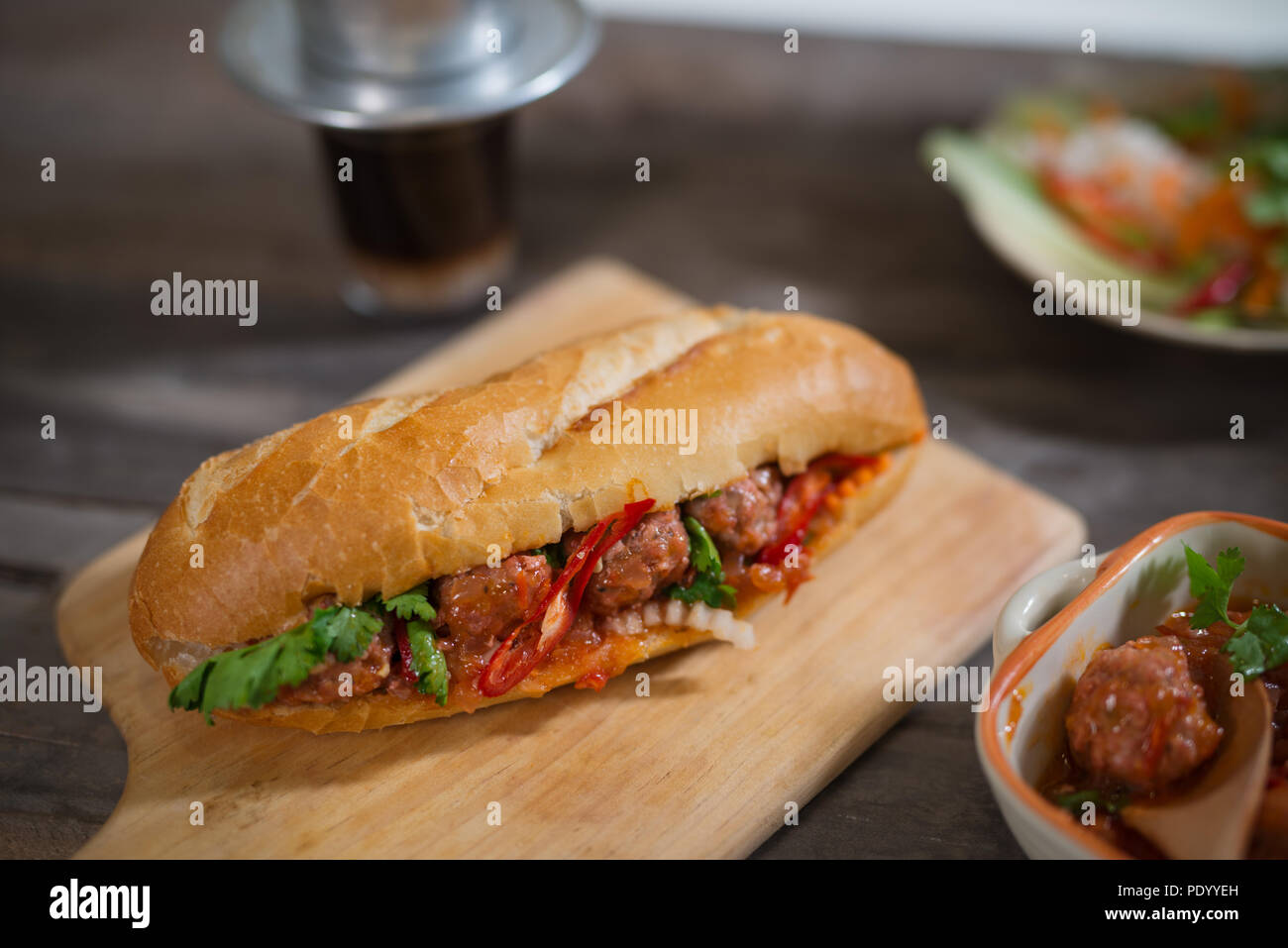 Vietnamese sandwich bread with meatballs in tomato sauce and radish, carrot pickle, cucumber, coriander. Stock Photo