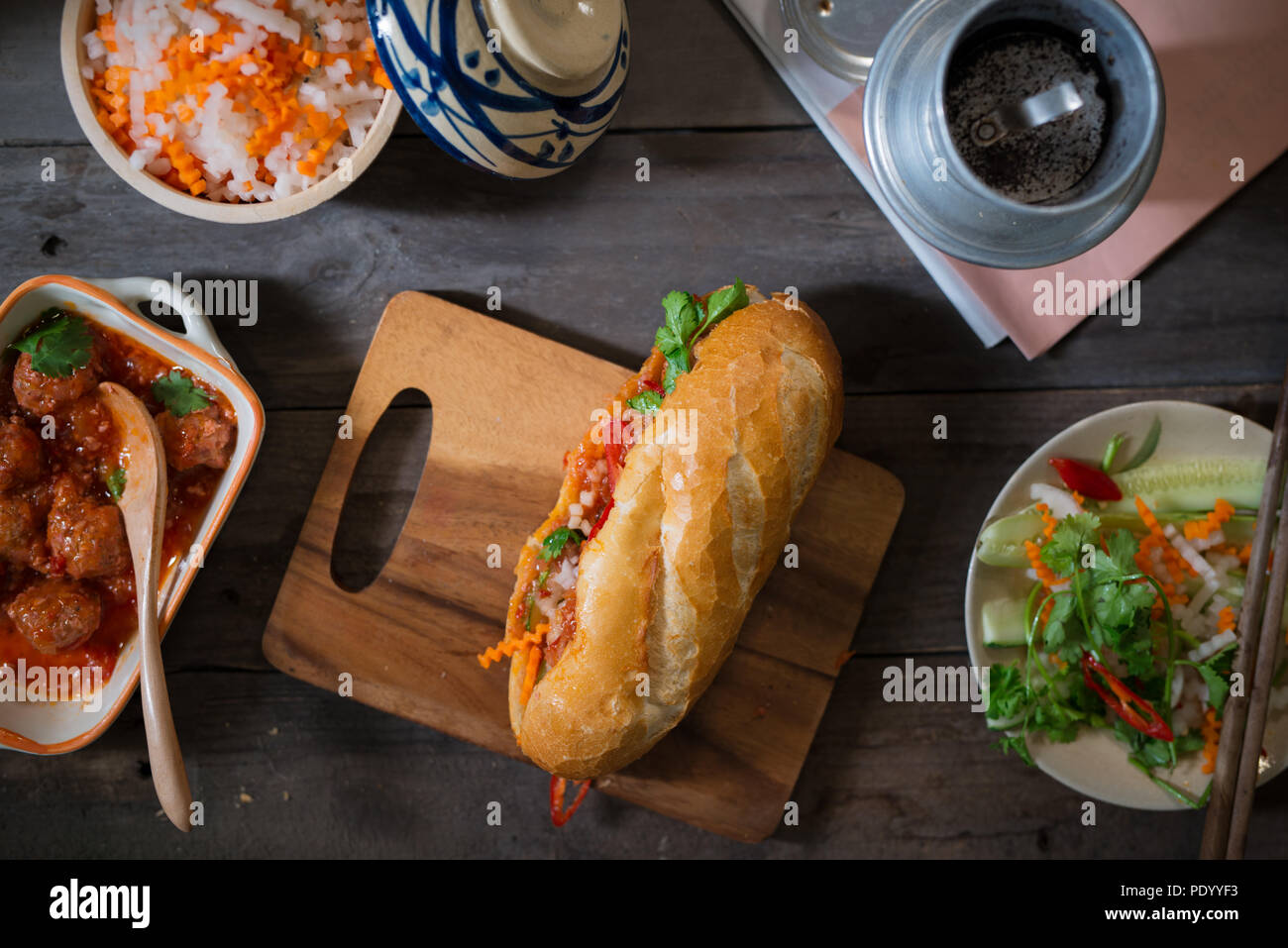 Vietnamese sandwich bread with meatballs in tomato sauce and radish, carrot pickle, cucumber, coriander. Stock Photo
