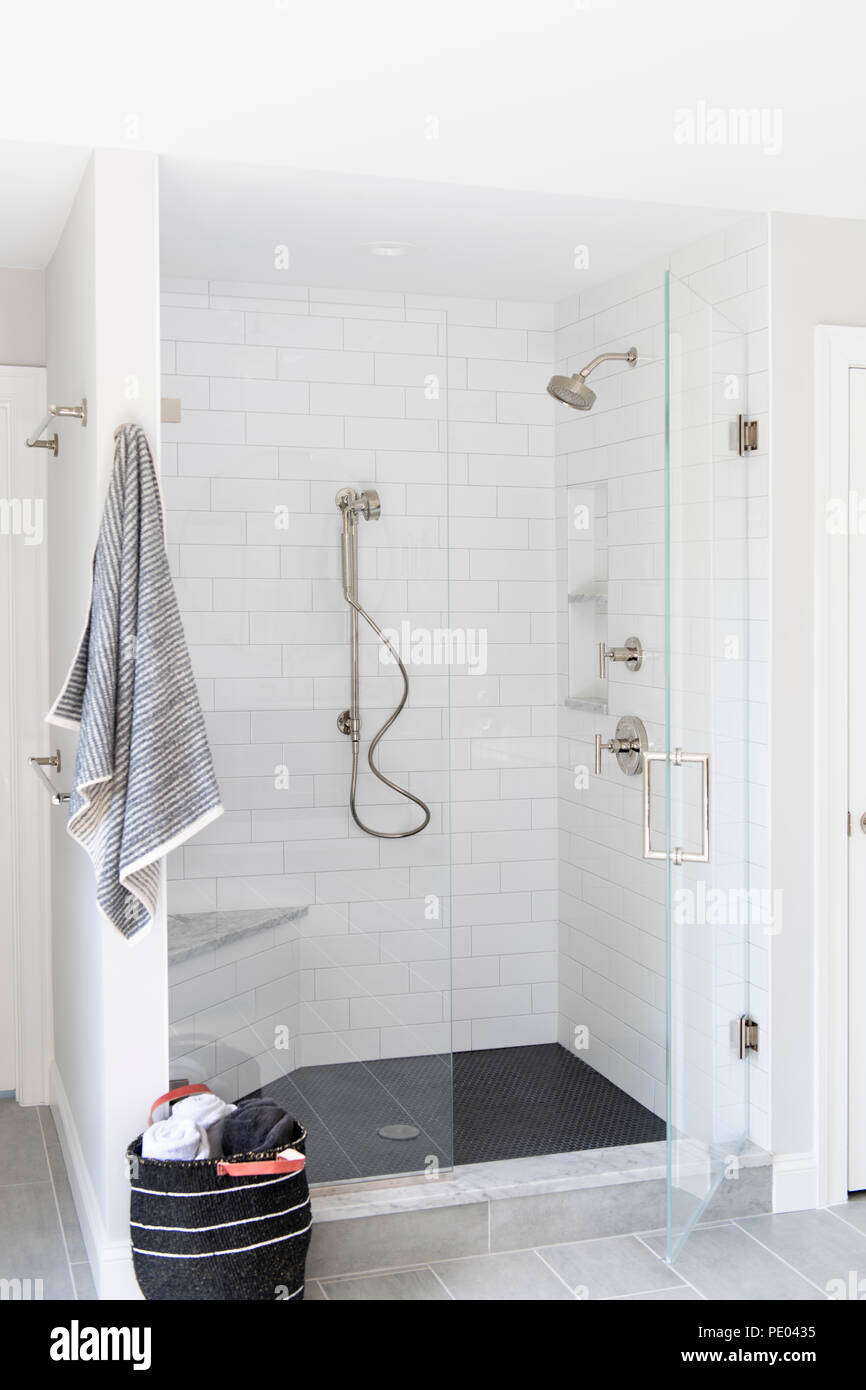 A high end residential bathroom shower stall with white tiles and towel Stock Photo