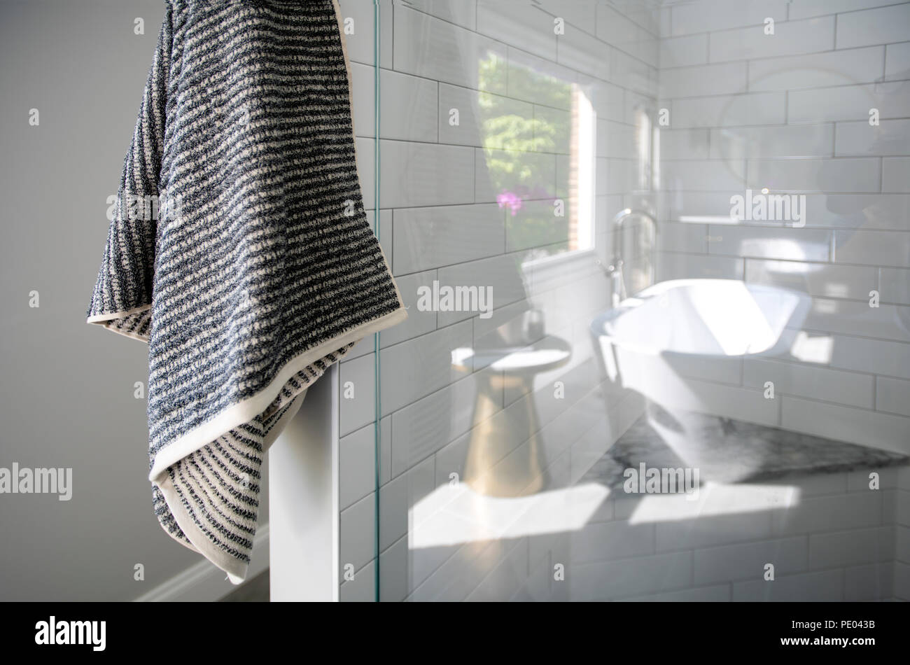 A high end residential bathroom shower stall with white tiles and towel Stock Photo