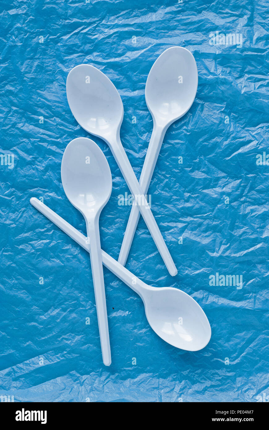 set of white plastic spoons on a blue plastic bag Stock Photo
