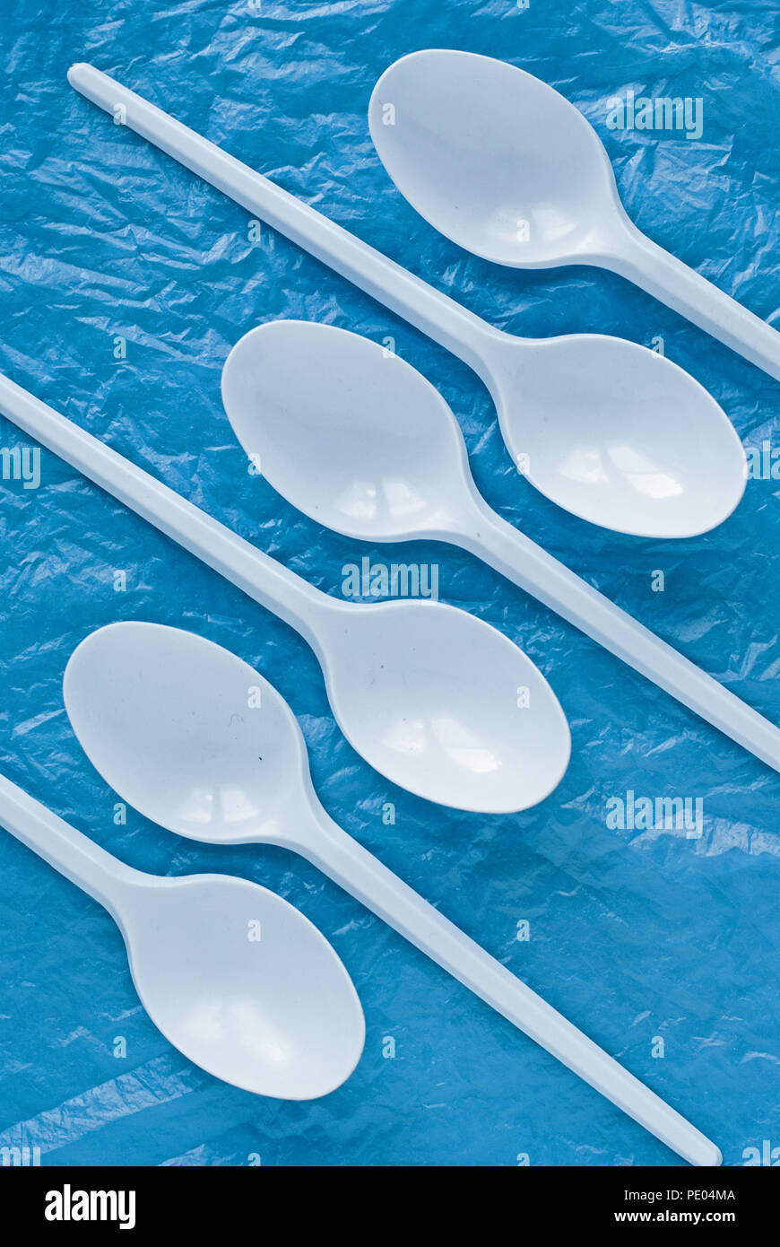 set of white plastic spoons on a blue plastic bag Stock Photo