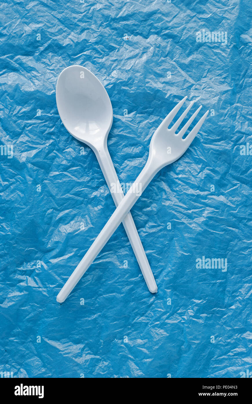 white plastic spoon and fork on a blue plastic bag Stock Photo