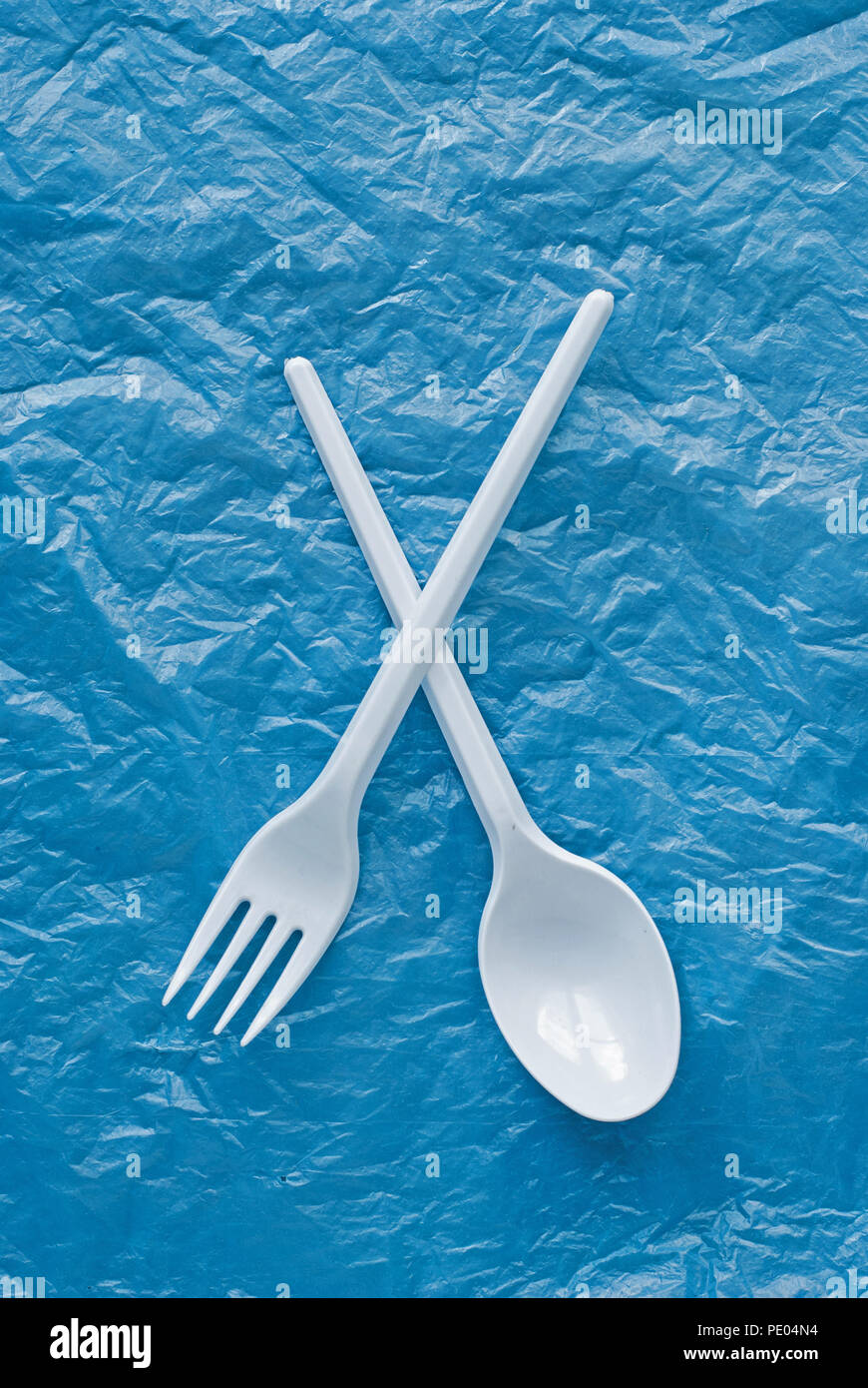 white plastic spoon and fork on a blue plastic bag Stock Photo
