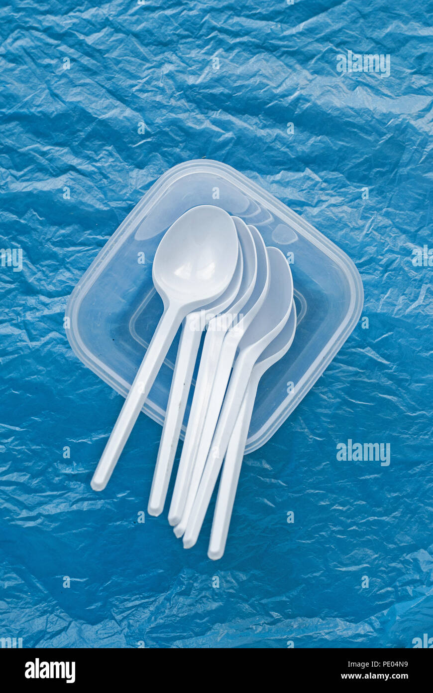 set of white plastic spoons in a plastic container on a blue plastic bag Stock Photo