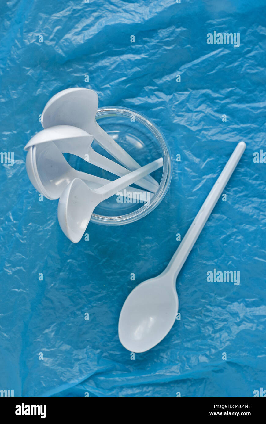set of white plastic spoons in a plastic container on a blue plastic bag Stock Photo