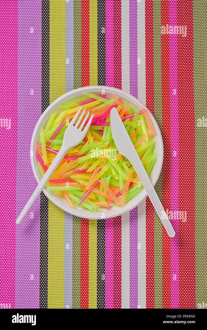 plate, fork, knife and pasta from plastic on a colored striped napkin Stock Photo