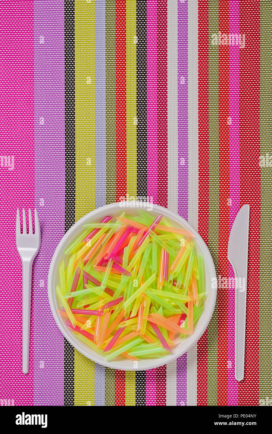 plate, fork, knife and pasta from plastic on a colored striped napkin Stock Photo