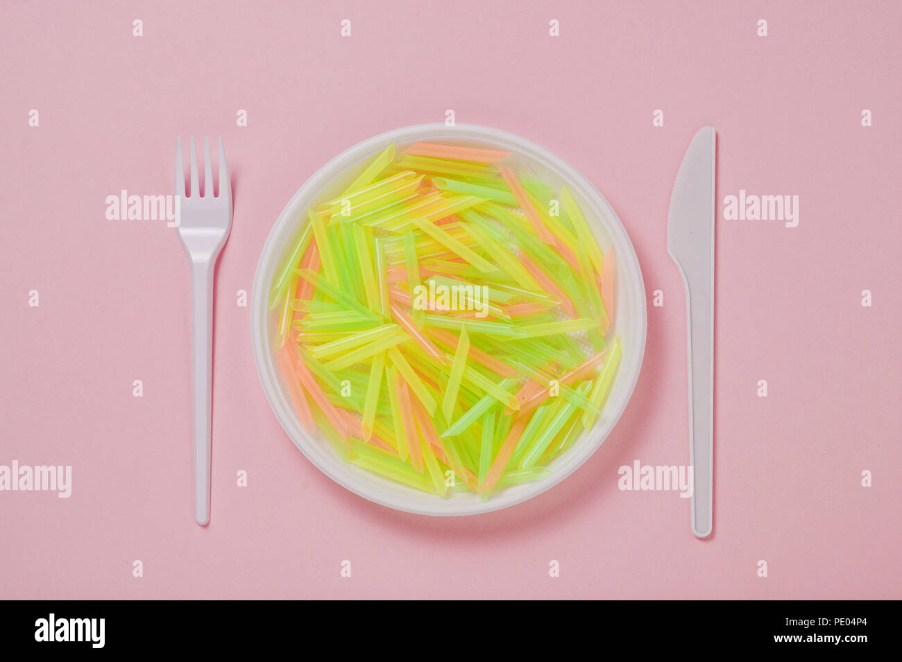 Plate, knife and fork of plastic on a pink background Stock Photo