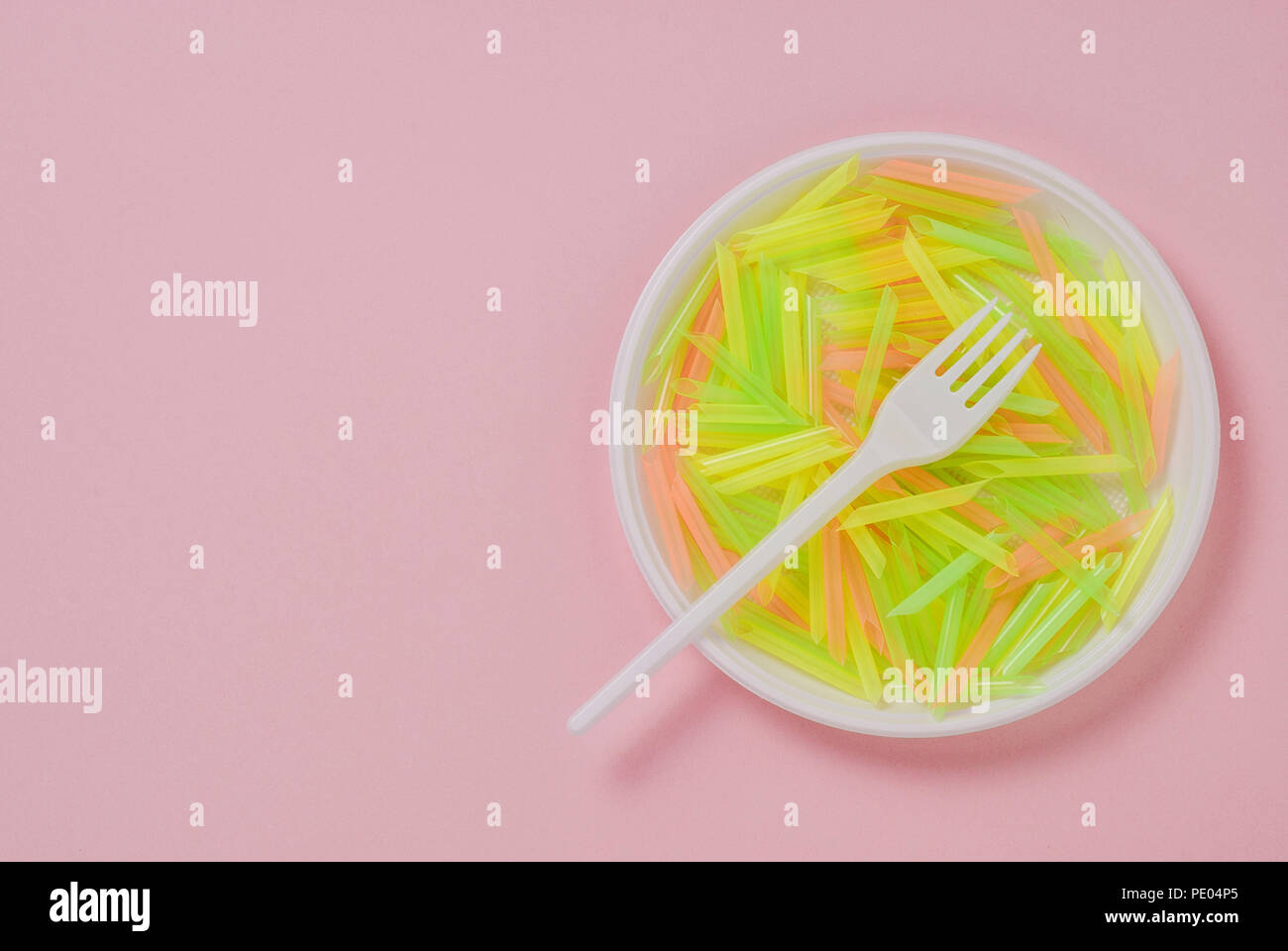 Plate and fork of plastic on a pink background Stock Photo