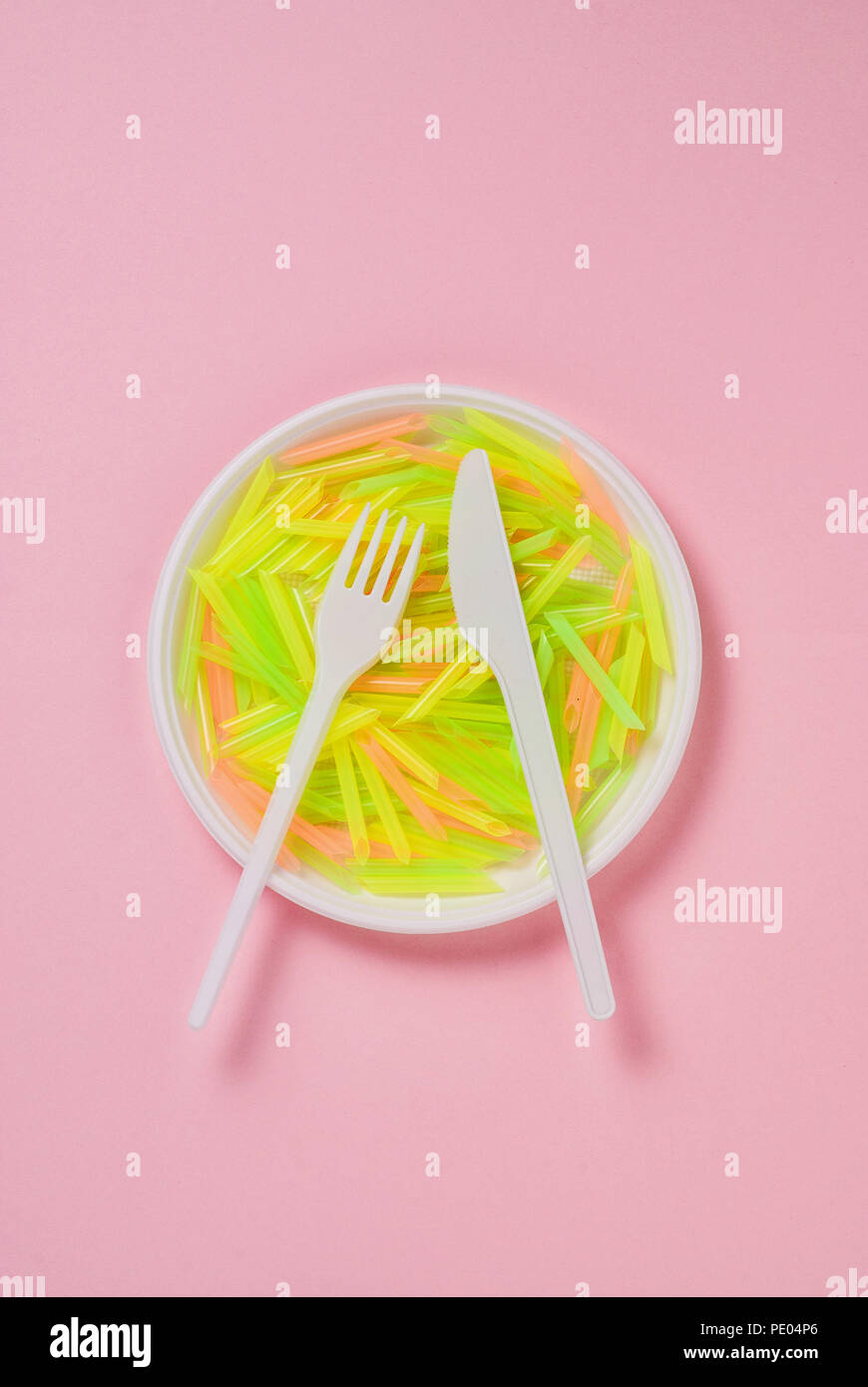 Plate, knife and fork of plastic on a pink background Stock Photo