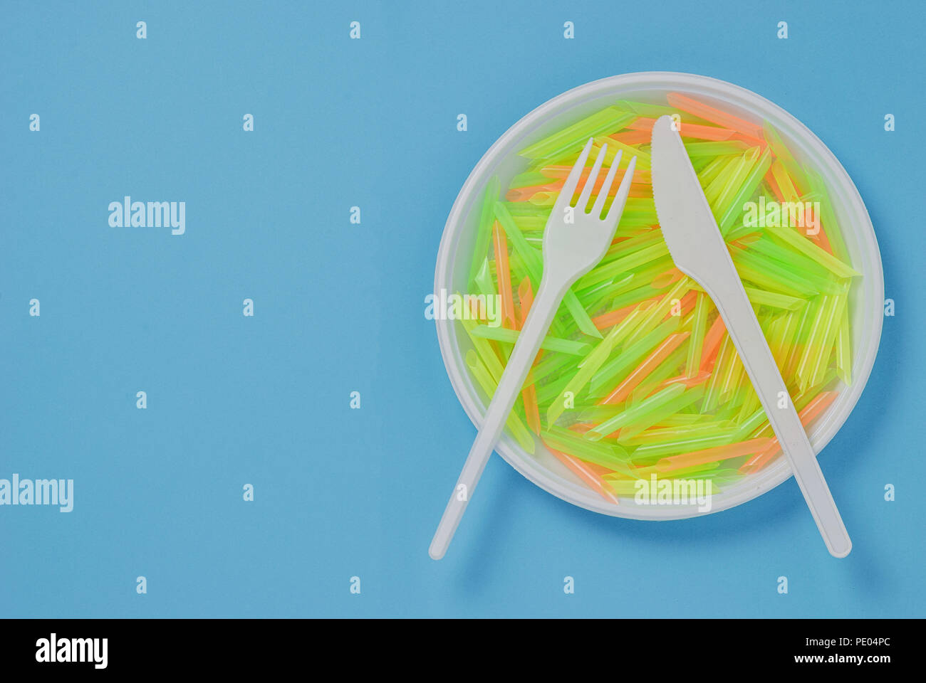Plate, knife and fork of plastic on a blue background Stock Photo