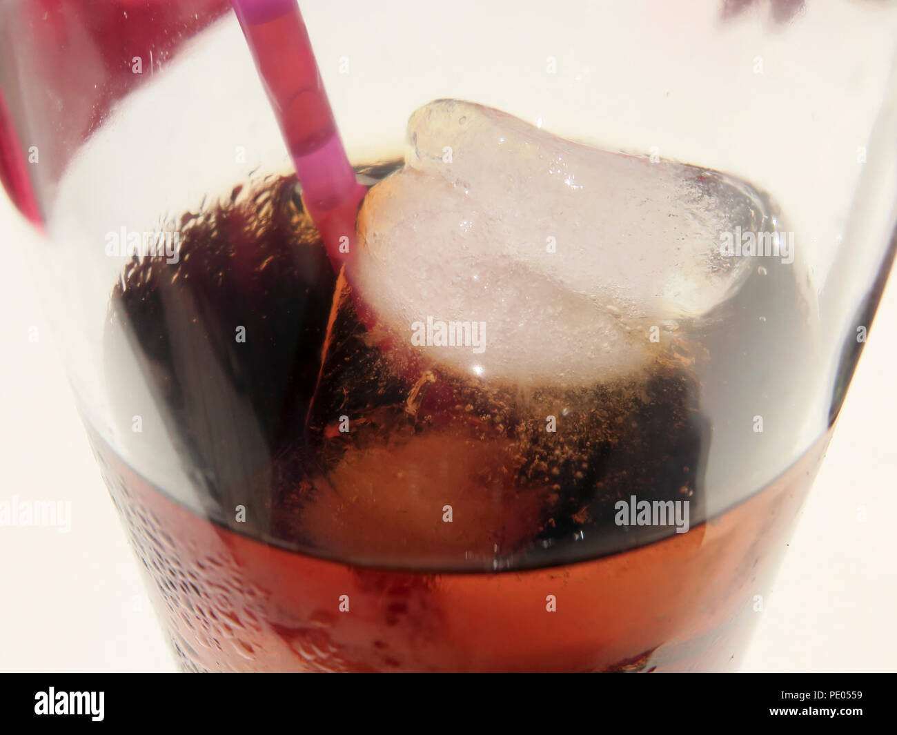 Close up of ice cubes and plastic straw in glass of coke Stock Photo