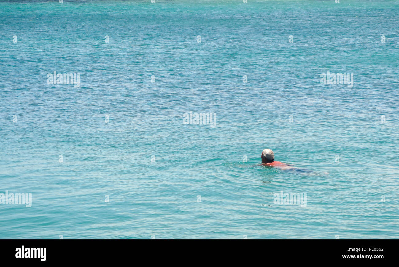 Older man swimming in sea in sunshine Stock Photo