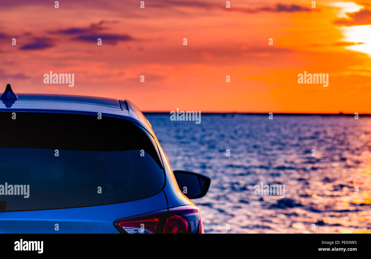 Blue compact SUV car with sport and modern design parked on concrete road by the sea at sunset. Environmentally friendly technology. Electric car tech Stock Photo