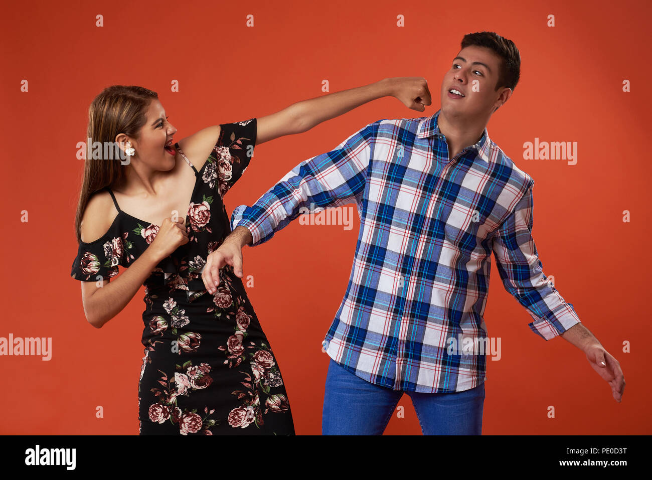 Funny fighting couple isolated on orange studio background Stock Photo